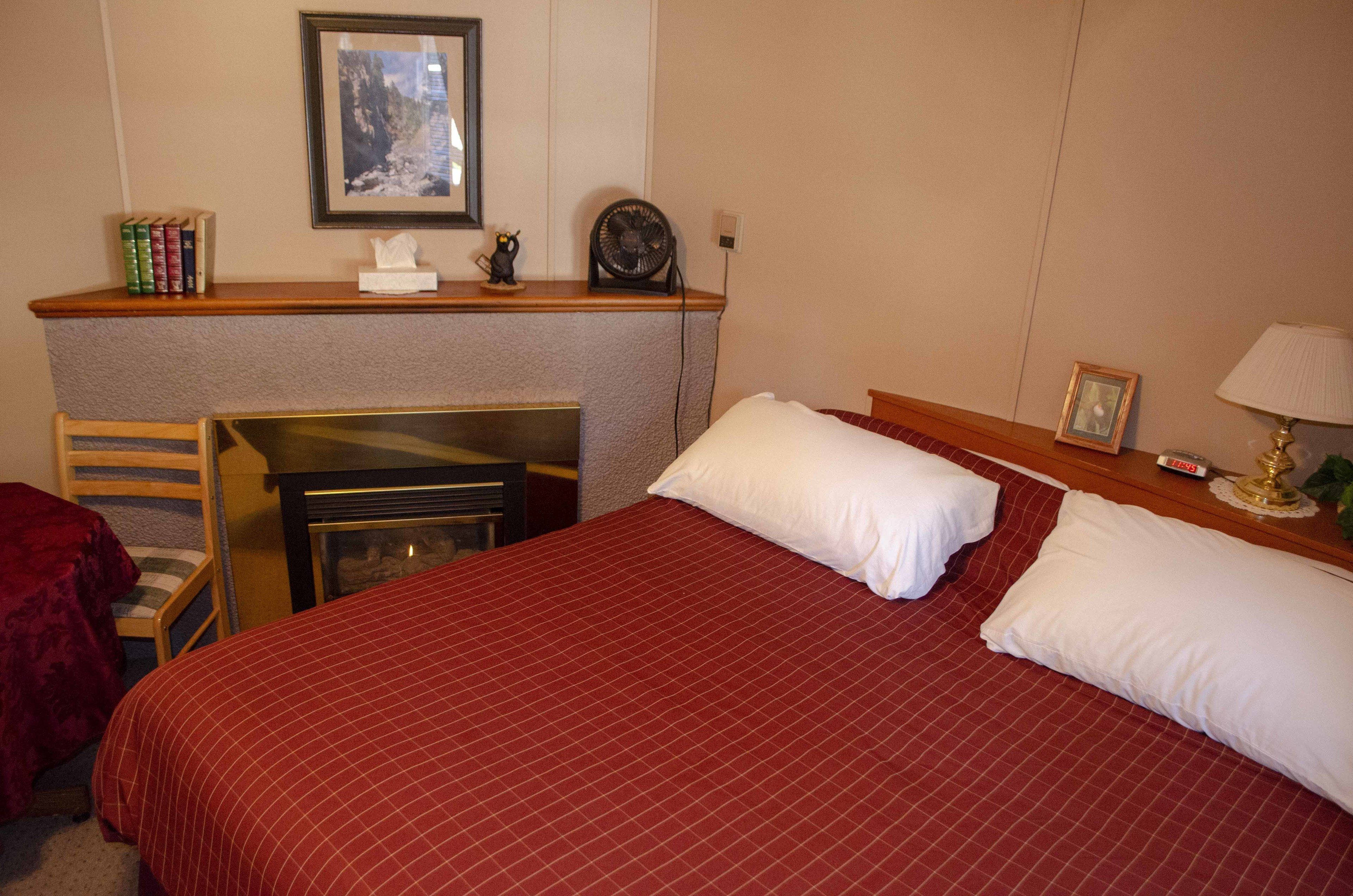 A hotel room with a large bed, a desk with a chair, a small table with a lamp, and a framed picture on the wall.
