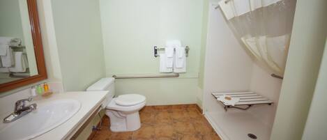 Un baño con un lavamanos blanco, inodoro y ducha. Hay toallas colgadas en la pared y un espejo sobre el lavamanos.