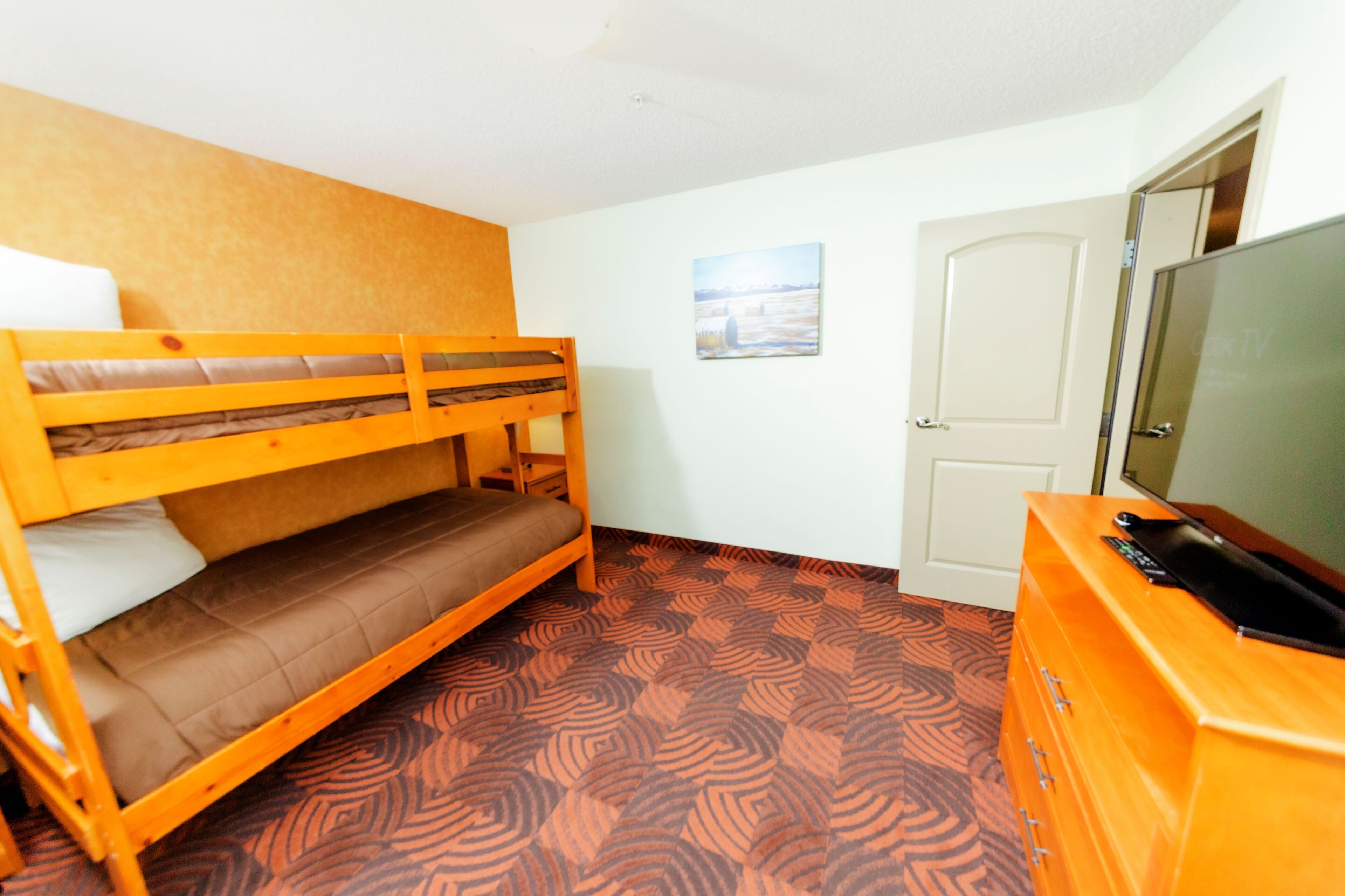 A room with a bunk bed, a television, a dresser, and a door.