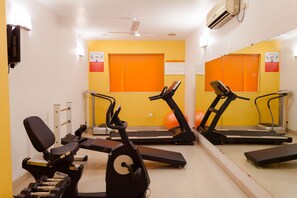 A gym with exercise equipment, a treadmill, and a stationary bike. - Ginger Vadodara (Vadodara)