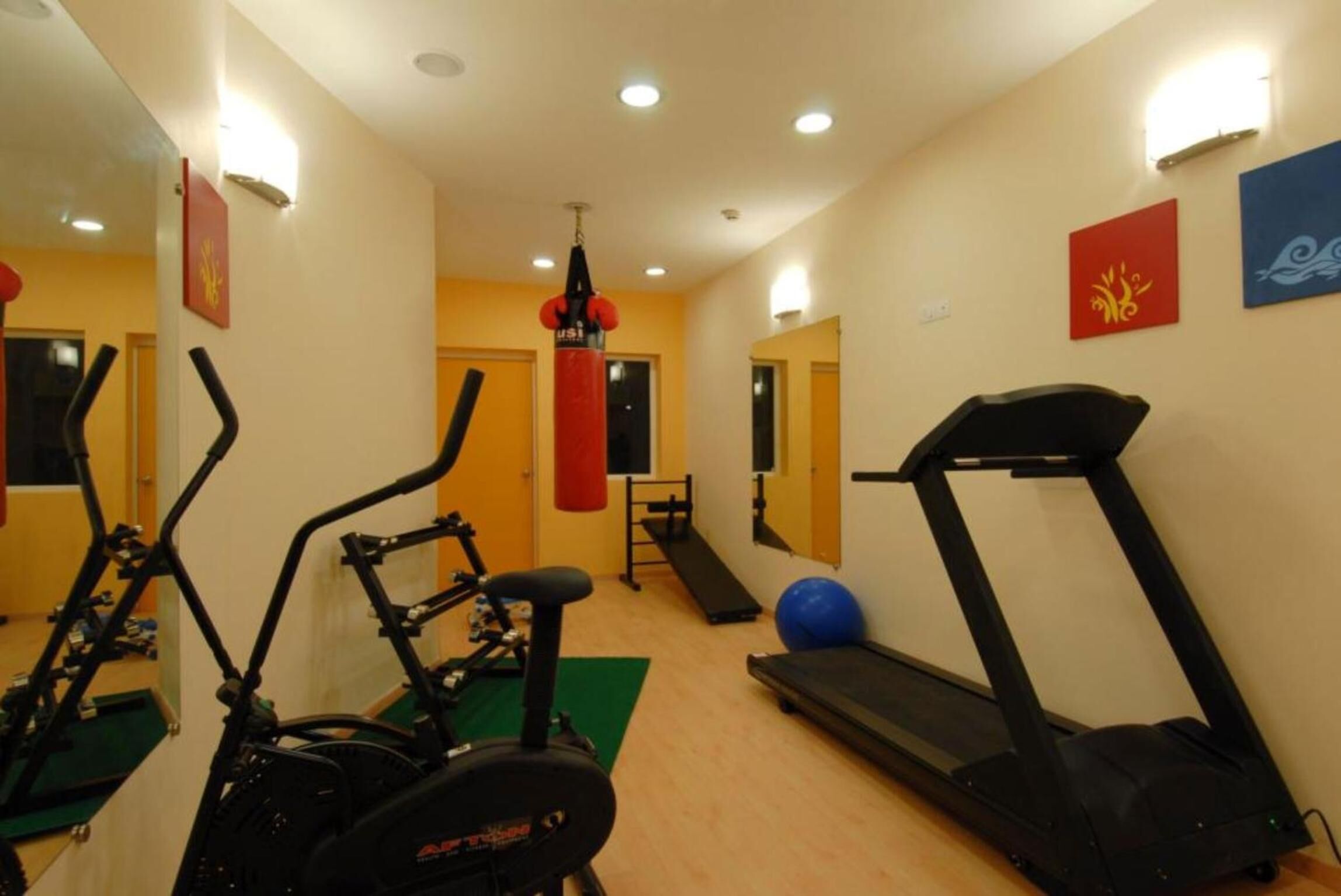 Un gimnasio con equipo de cardio, un saco de boxeo y una cinta de correr.