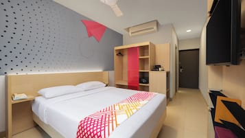 A hotel room with a bed, a bedside table with a phone, a wardrobe, a TV, and an air conditioning unit.