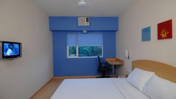 Una habitación de hotel con una cama, un escritorio, una silla, un televisor y una ventana.