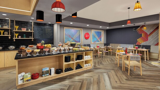 Un restaurante moderno con una barra de madera, un tablero de menú negro y coloridas obras de arte en la pared.