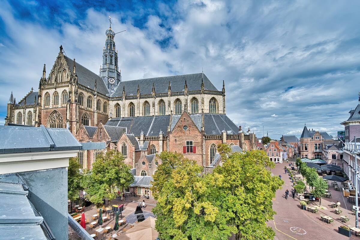 A historic church with a tall tower, surrounded by a town square with outdoor seating and trees.