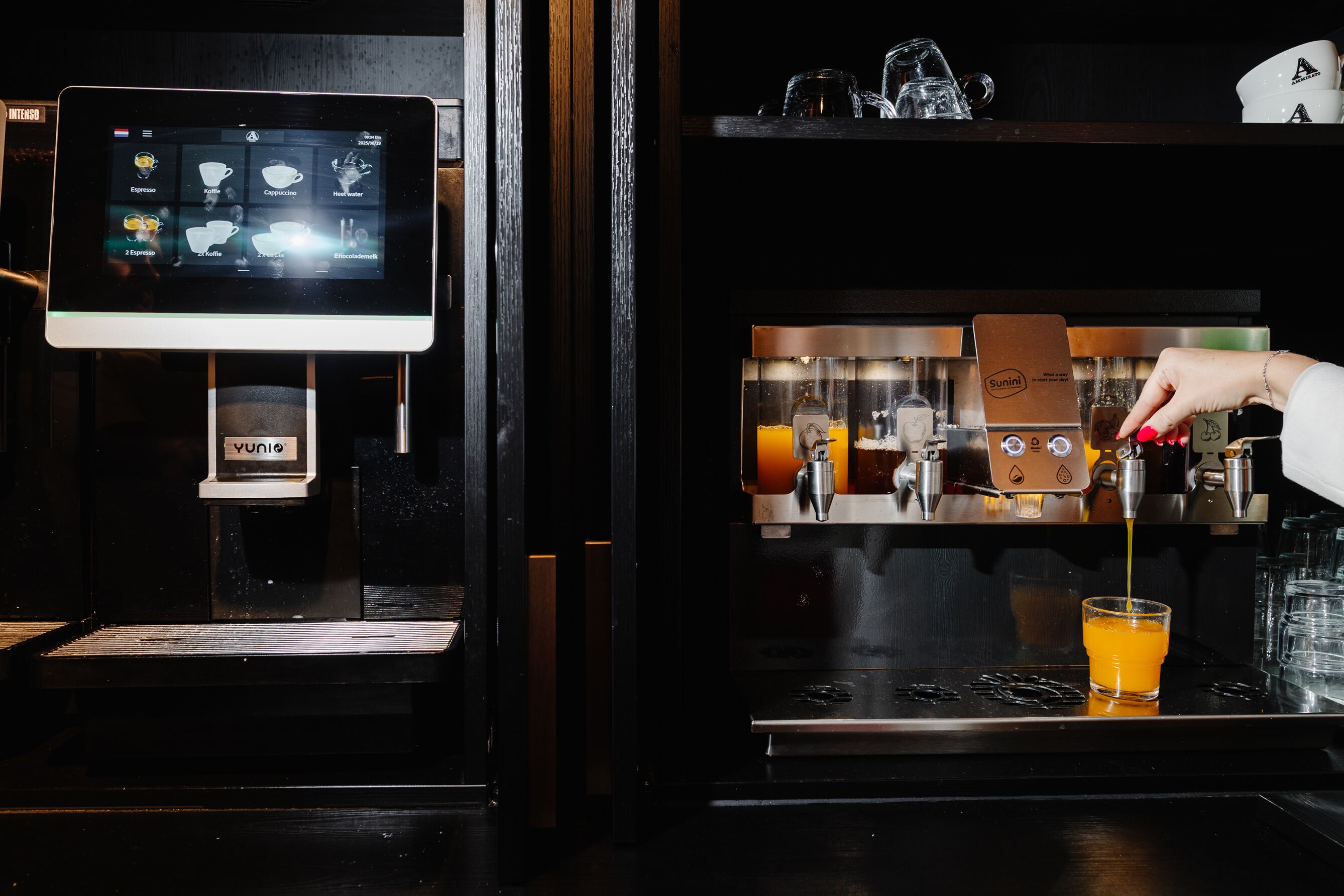 Una cafetera sirviendo una bebida en un vaso, una pantalla digital con el menú y un dispensador de cápsulas de café.