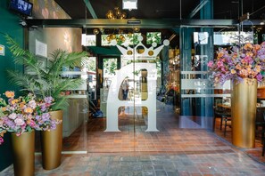 A hotel entrance with a glass door, large potted plants, and a decorative metal sign. - Ambassador City Centre Hotel (Haarlem)