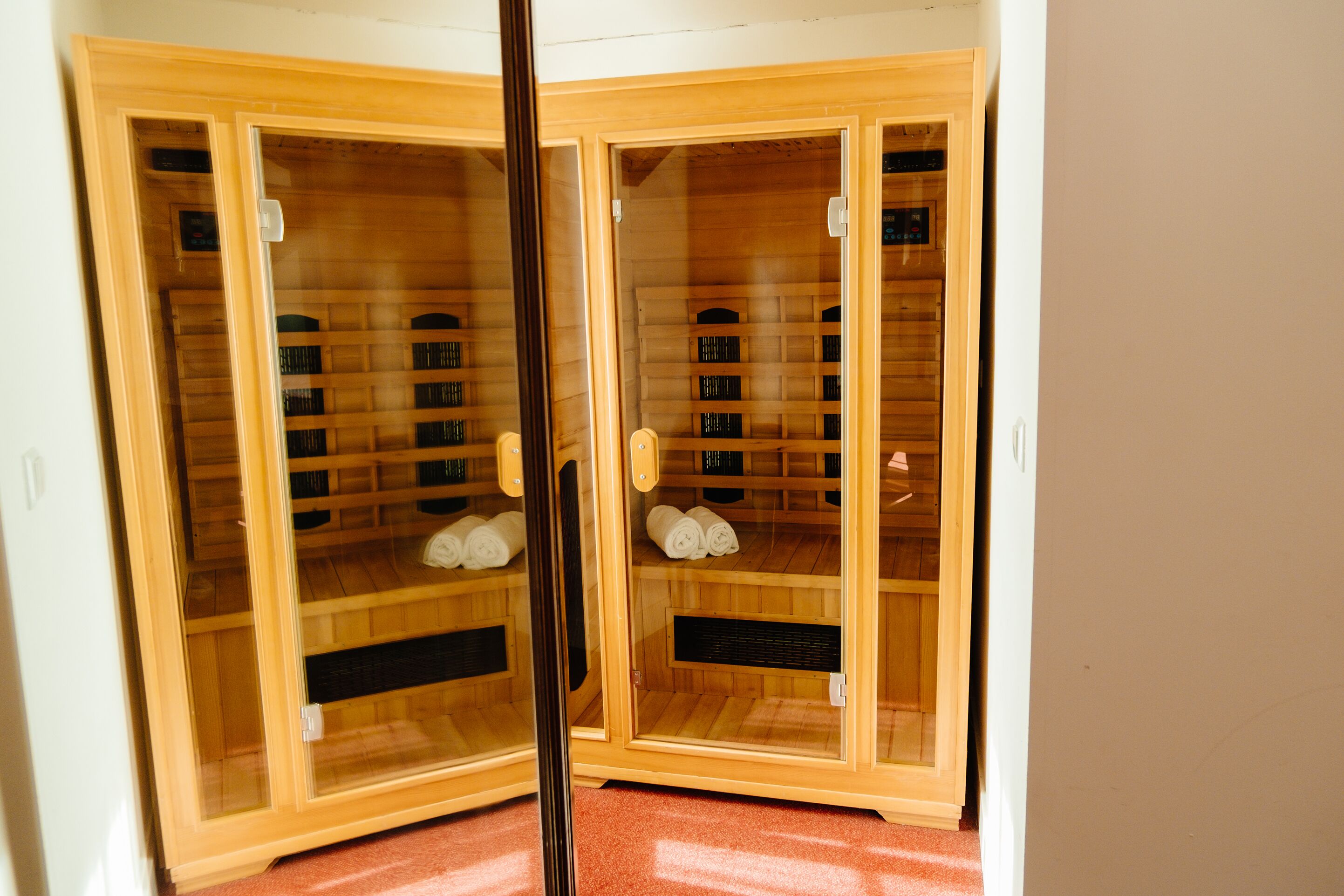 A wooden cabinet with glass doors containing neatly rolled towels and a control panel.