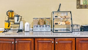 A kitchenette with a coffee maker, a toaster, and a bread display.