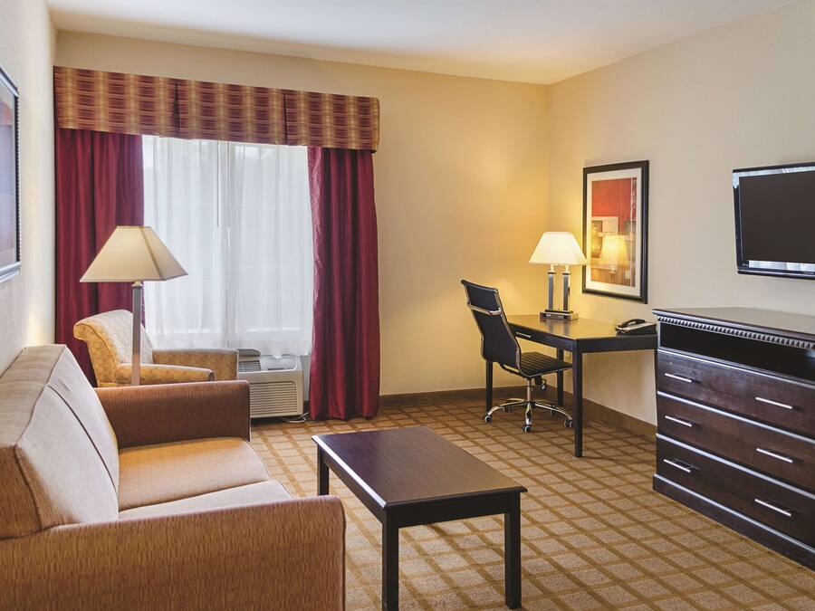 Une chambre d’hôtel équipée d’un canapé, d’un bureau, d’une chaise, d’une télévision et d’une lampe.