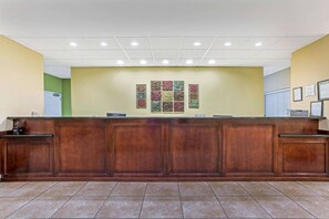 A reception desk with a wooden finish, a tiled floor, and a wall with framed artwork.