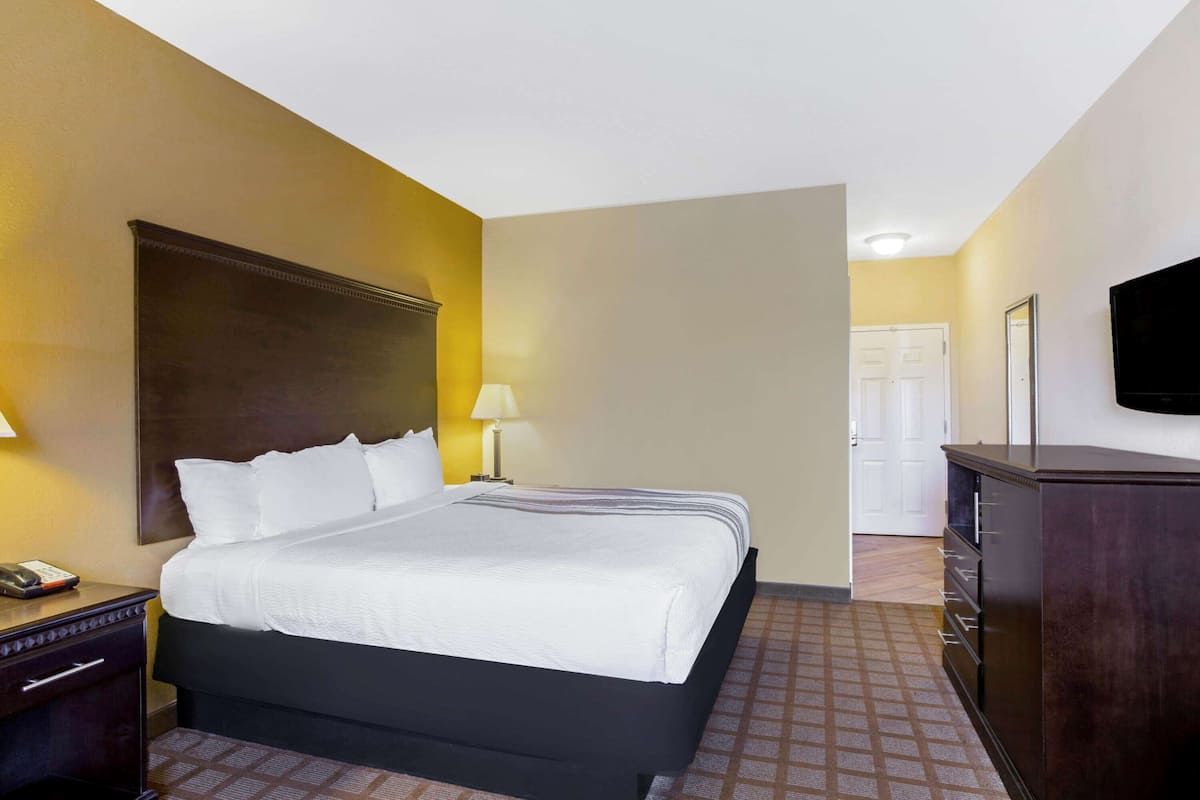Une chambre d’hôtel avec un grand lit, des tables de chevet, une commode et un téléviseur fixé au mur.
