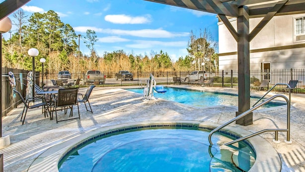 A pool area with a hot tub, lounge chairs, and a covered seating area.