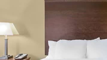 Una habitación de hotel con una cama, una lámpara de noche y un teléfono sobre una mesita de madera.