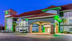 A hotel with a prominent 'La Quinta' sign, a covered entrance, and a parking lot with several vehicles.