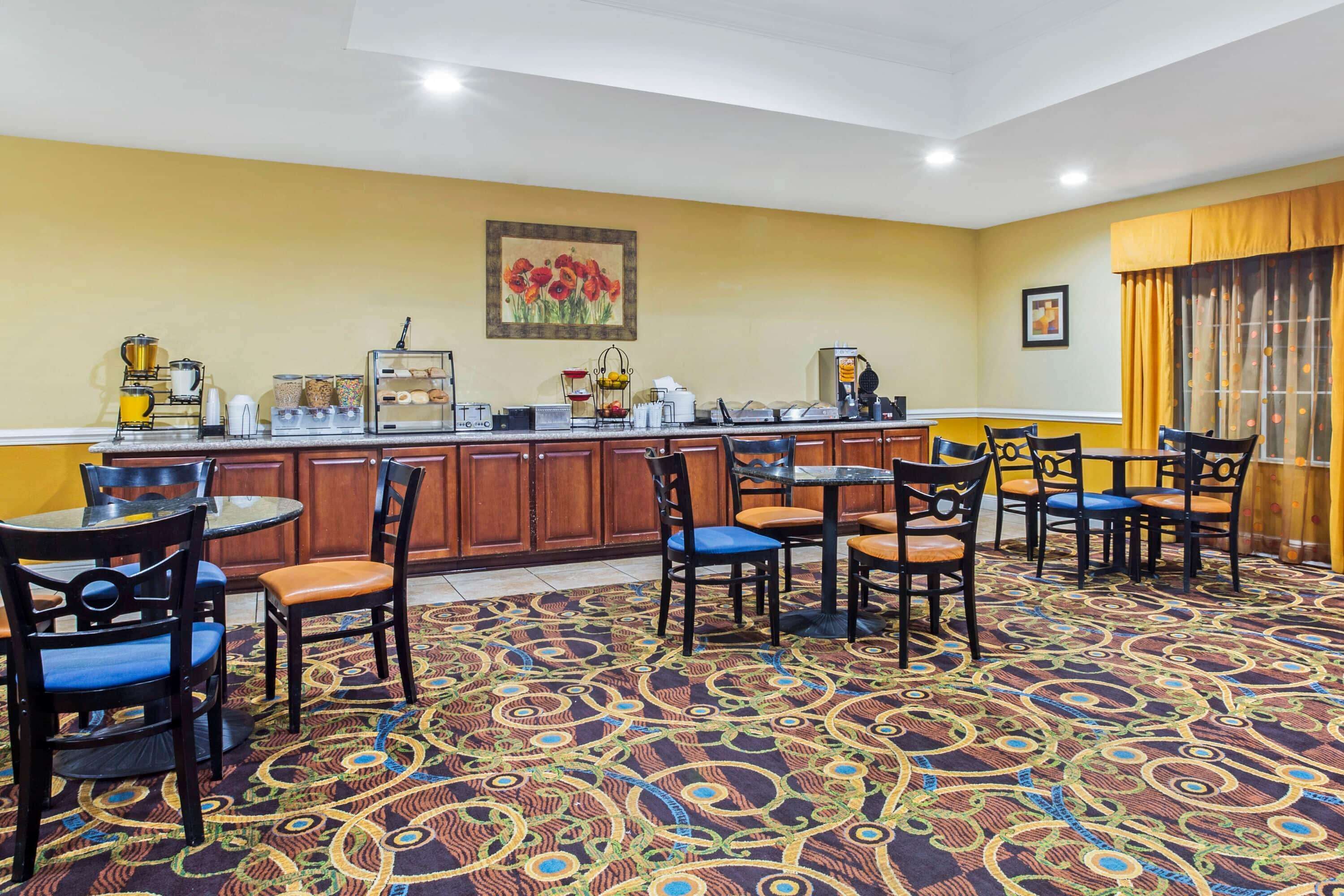 A hotel lobby with a bar area, multiple seating arrangements, and a patterned carpet.