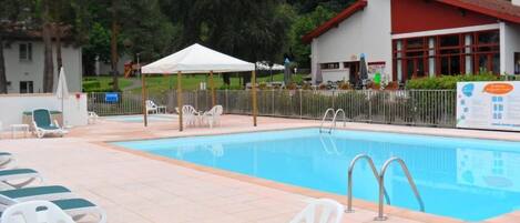 Una piscina con sillas de descanso blancas y una carpa blanca.