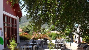 An outdoor seating area with tables and chairs, surrounded by potted plants and a view of a hillside. - VVF Résidence Pays Basque Saint-Jean-Pied-de-Port (Saint-Jean-Pied-de-Port)
