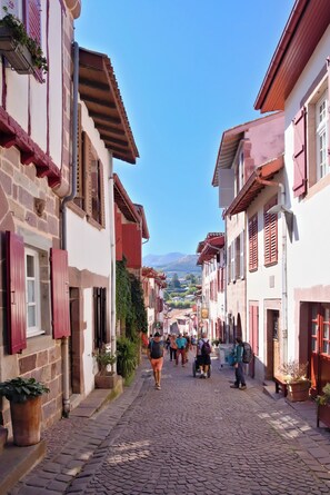 A cobblestone street lined with buildings featuring red shutters and stone facades. - VVF Résidence Pays Basque Saint-Jean-Pied-de-Port (Saint-Jean-Pied-de-Port)