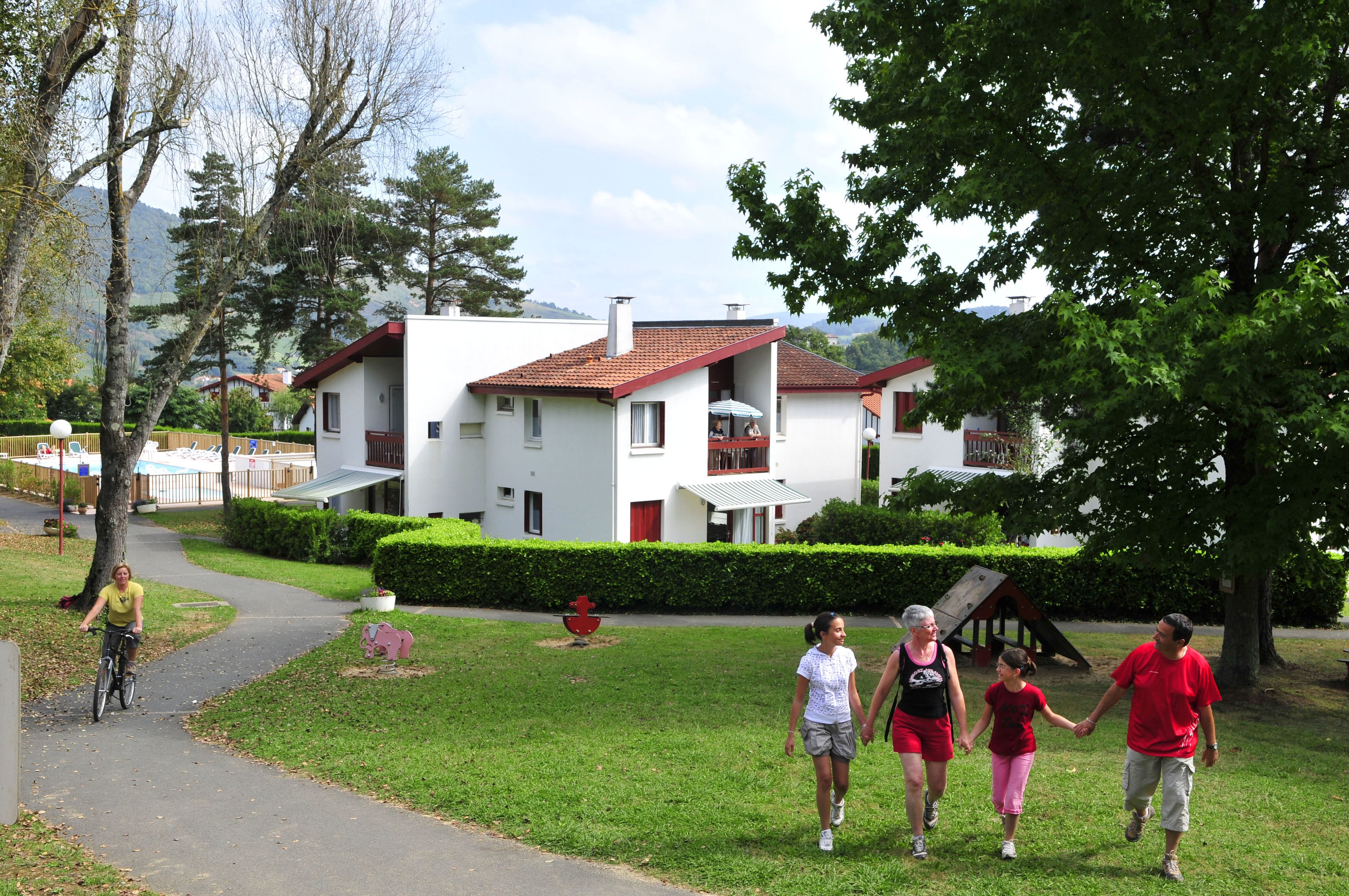 Una zona residencial con un sendero, un pequeño jardín y un edificio blanco de techo rojo.