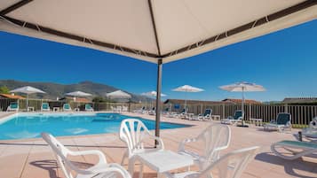 Una piscina al aire libre de temporada, sombrillas