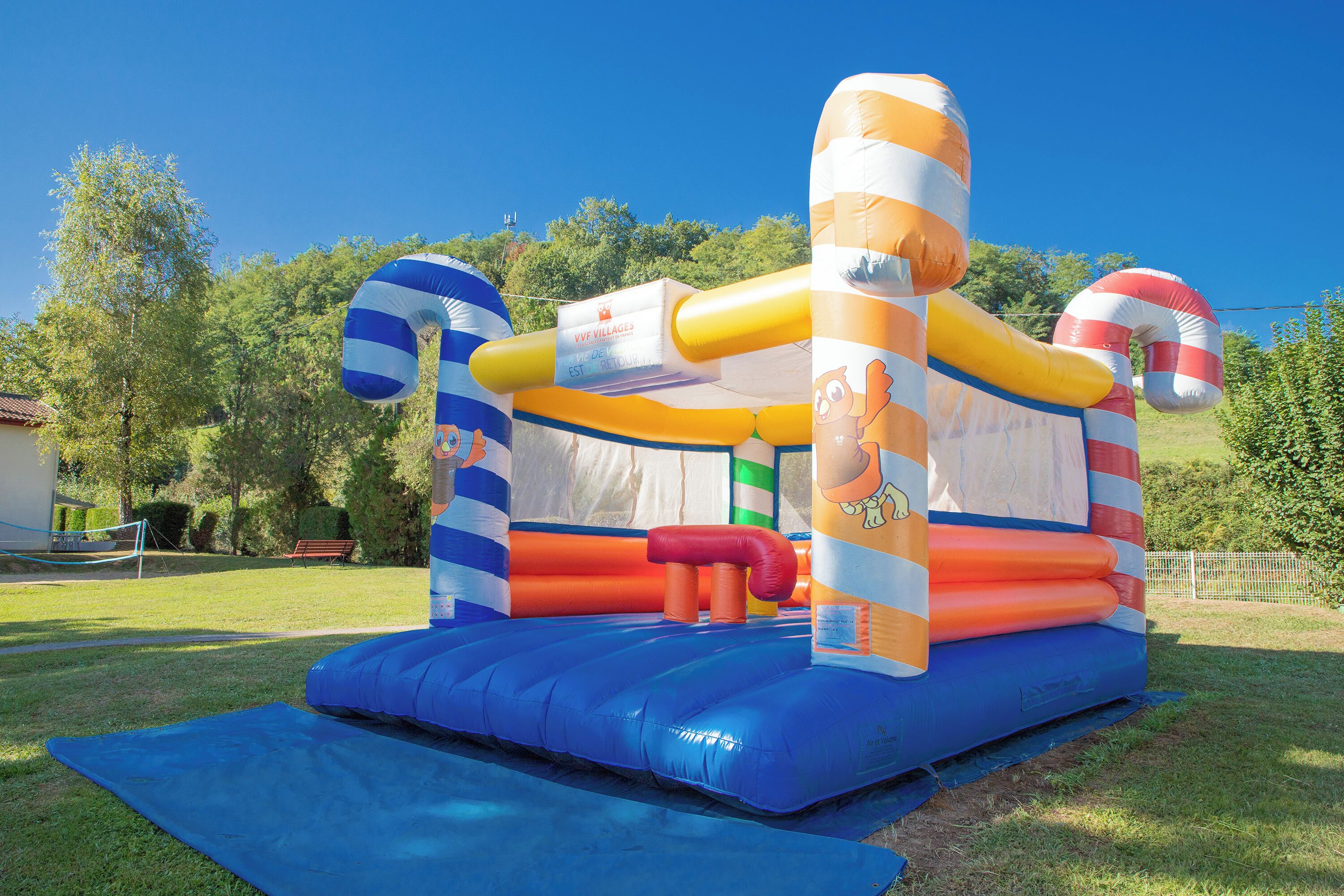A large inflatable bouncy castle with a cartoon character design, set up on a grassy area.