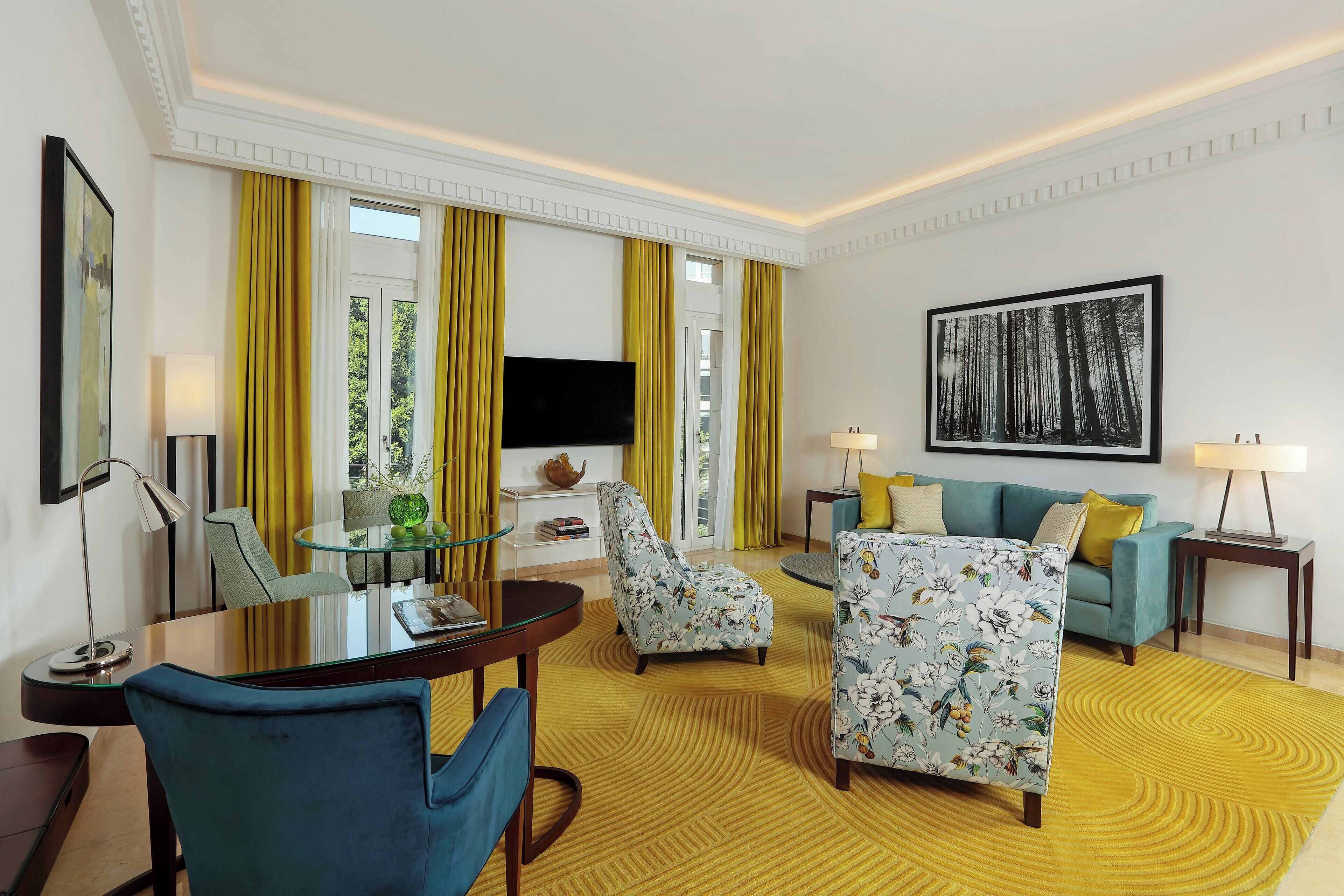 Una camera d'albergo moderna con zona pranzo, divano, poltrona e televisore.