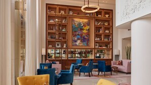 A modern library with a large bookshelf, comfortable seating, and a large abstract painting. - Le Gray (Beirut)