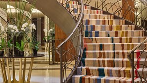 A modern interior with a spiral staircase, a round table with plants, and a patterned carpet. - Le Gray (Beirut)