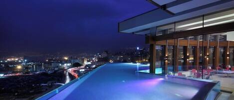 A modern building with a glass facade and a pool area.