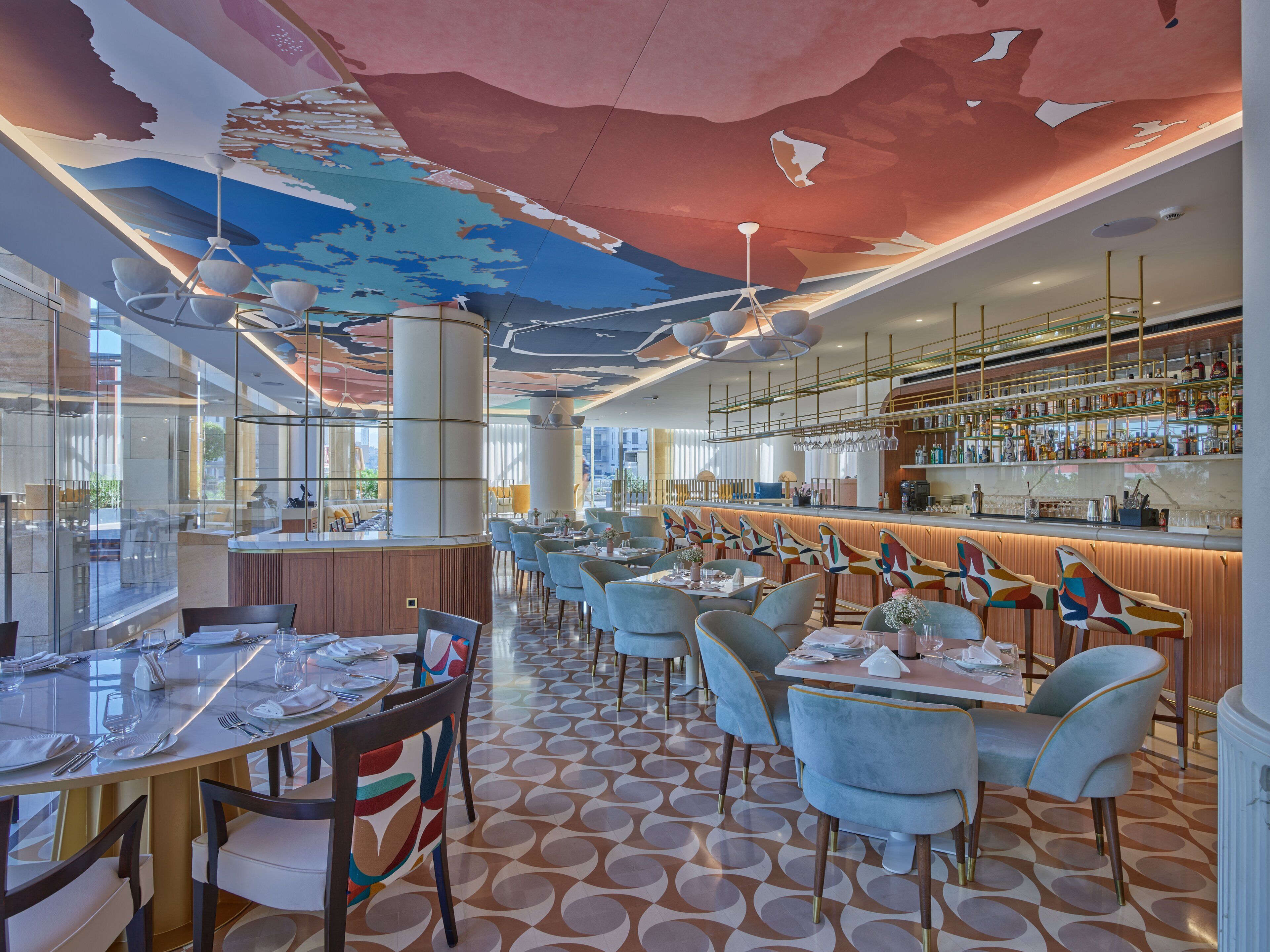 A modern restaurant interior with a bar area, round tables, and chairs.