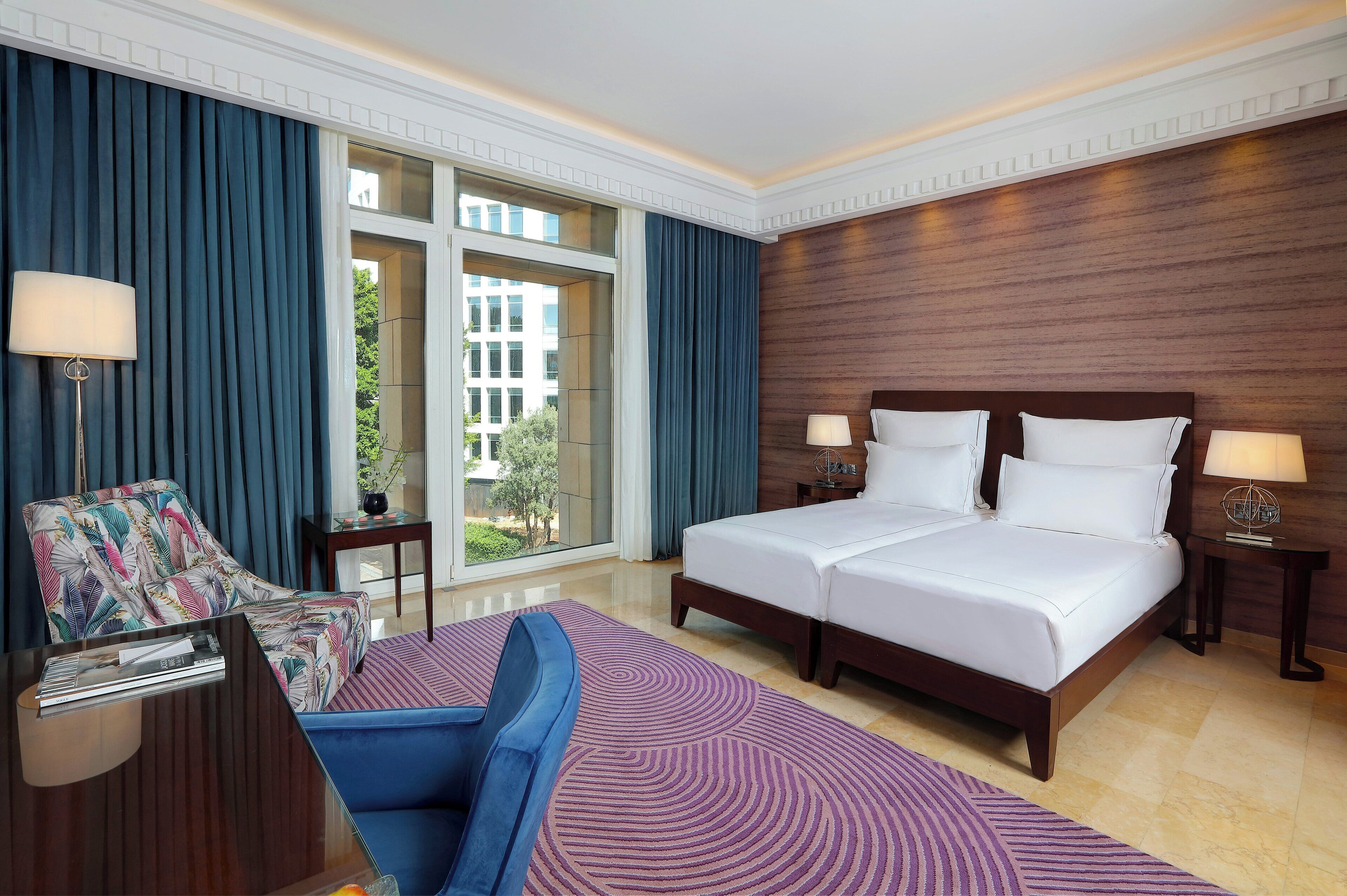 Habitación de hotel con una cama grande, un sofá, un escritorio y vistas al exterior.