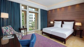 Habitación de hotel con una cama grande, un sofá, un escritorio y vistas al exterior.