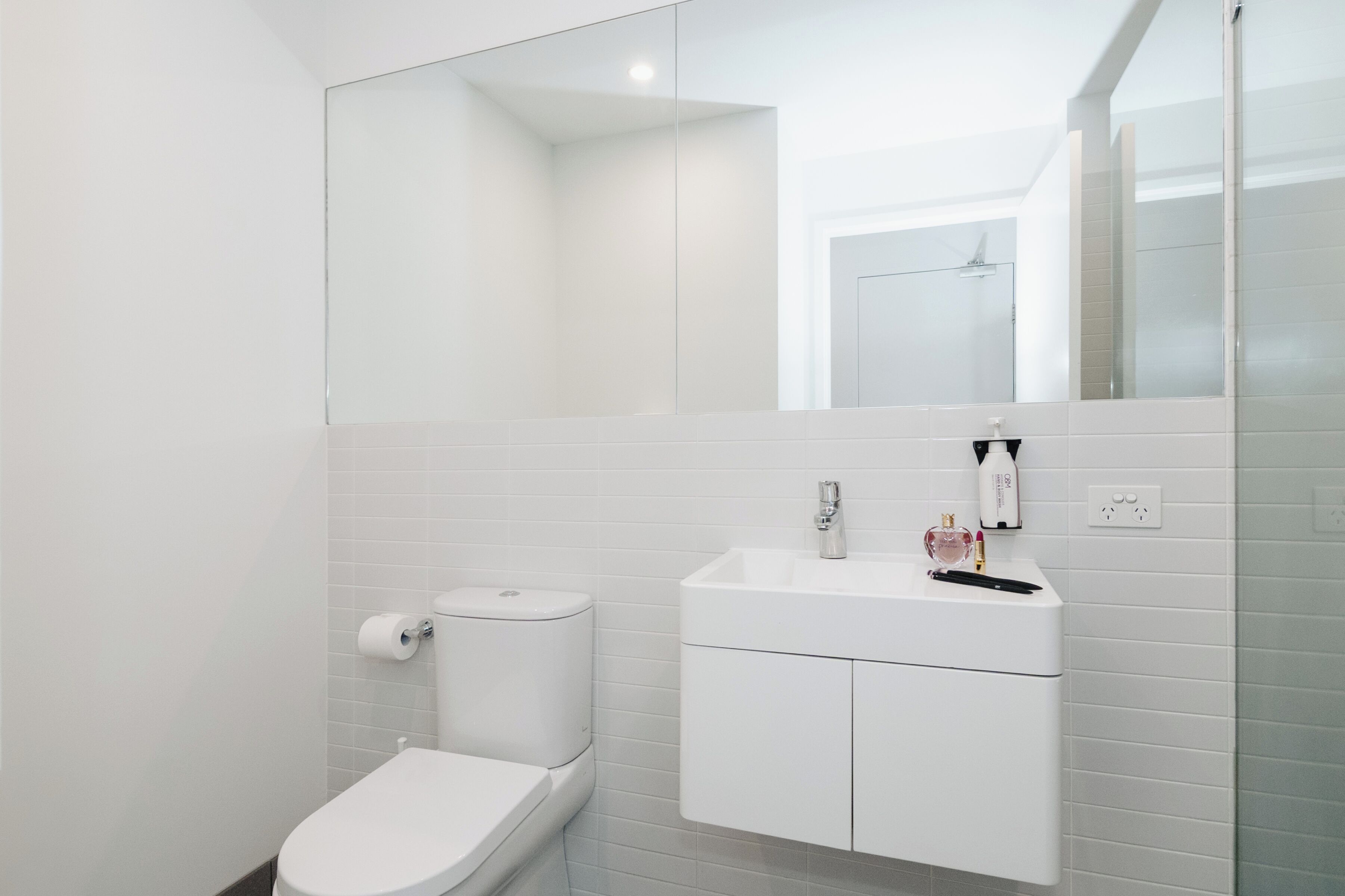 Une salle de bain moderne avec des toilettes, un lavabo et un miroir.