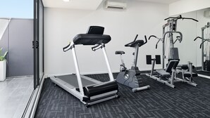 Une salle de sport moderne équipée de tapis de course, de vélos elliptiques et de matériel de musculation.