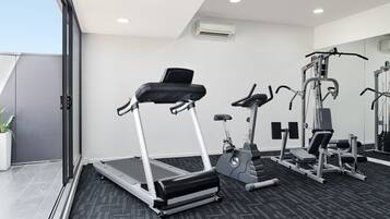 A modern gym with treadmills, elliptical machines, and weight equipment.