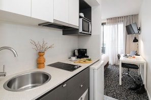 A modern kitchen with a built-in microwave, a coffee maker, and a sink.