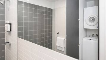 Un baño moderno con ducha, toallero y lavadora integrada.