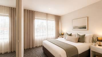 Habitación de hotel con una cama grande, dos mesitas de noche con lámparas, un cuadro en la pared y vistas a través de la ventana.
