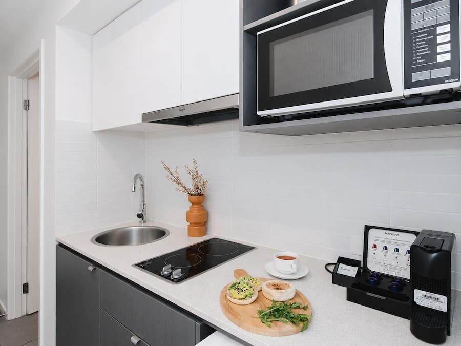 A modern kitchen with a built-in microwave, a coffee machine, and a sink.