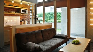 A modern kitchen with a microwave, shelves, and a window overlooking a garden. - La Gioia Designers Lofts Luxury Apartments (Kraków)