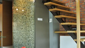 A modern interior with a wooden staircase, a stone wall, and a small table with apples. - La Gioia Designers Lofts Luxury Apartments (Kraków)