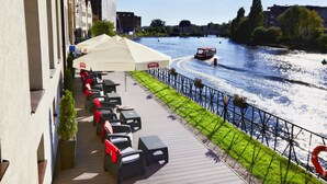 A riverside terrace with outdoor seating and a view of the river. - Qubus Hotel Gdansk (Gdansk)