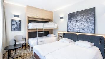 Ett hotellrum med våningssängar, ett skrivbord och en stor tavla på väggen.