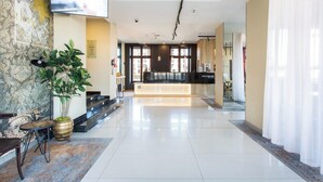 A modern hotel lobby with a reception desk, a large potted plant, and a flat-screen TV mounted on the wall. - Qubus Hotel Gdansk (Gdansk)
