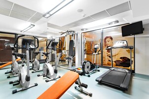 A gym with various exercise equipment including treadmills, stationary bikes, and weight machines.