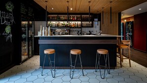 A modern bar area with a wooden ceiling, hexagonal tiled floor, and a bar counter with stools. - Qubus Hotel Gdansk (Gdansk)