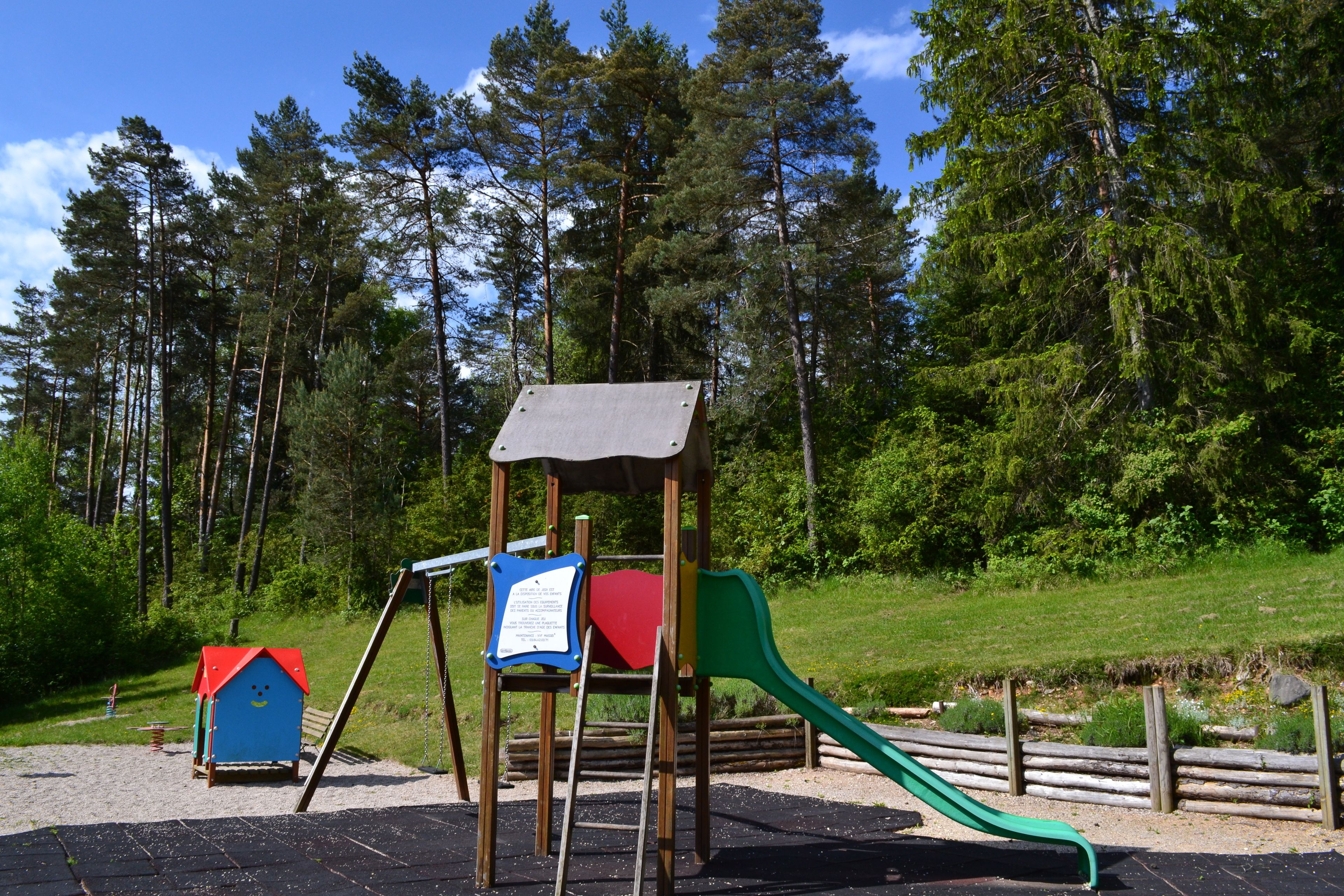 A playground with a swing set, slide, and small playhouse.