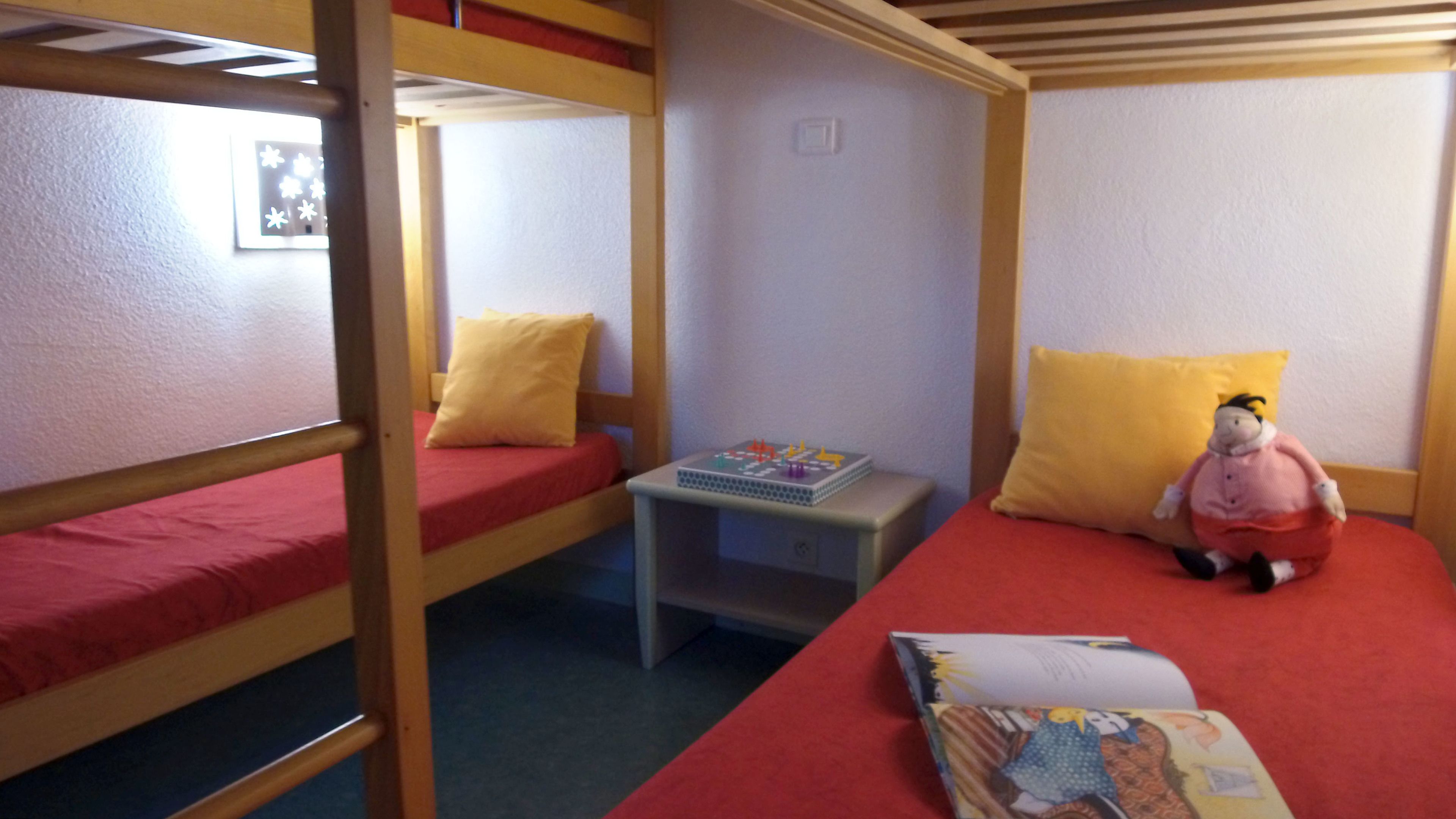 A bunk bed room with a small table, a toy, and a book.