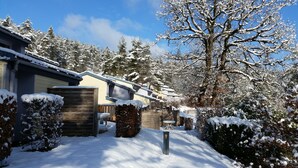 A snow-covered residential area with houses, a wooden fence, and snow-laden trees. - VVF Jura Lac de Vouglans, Maisod (Maisod)